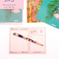 Close up image of selected bright tropical postcards, with the back of one postcard facing up, by Jack & Orla