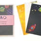 A photo featuring three of the designs in the space themed postcard gift set, as well as a packaged set. The front postcard has a navy background with stars, brightly coloured planets and a red rocket.